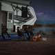 A photo of two people setting up camp by their RV.